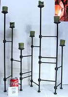 Front view of black cast iron adjustable candelabra candle holder with seven candle holders and a Coca-Cola can for scale.