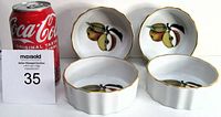 Four matching small porcelain dishes with apple design, gold trim, and scalloped edges. Three have original labels attached. Shown with Coca-Cola can for scale.
