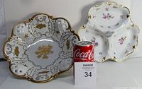 Photo showing two porcelain pieces: a white porcelain reticulated lattice serving bowl with gold leaf, and a white three compartment tray with floral patterns and gold trim, both with ornate rims next to a Coca-Cola can for scale.