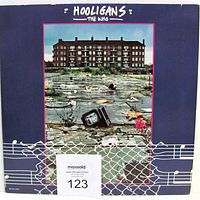 Front cover of 'Wholigans' double LP gatefold jacket showing flooded urban scene with abandoned television and apartment building.