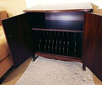 Interior view with double doors open revealing vertical dividers for sheet music or vinyl storage inside the cabinet.