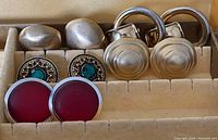 Photo shows five pairs of earrings in a display box, featuring various designs and colors as detailed in the lot description.