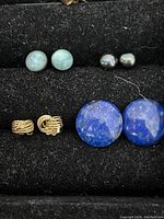 Four pairs of various earrings on a black display stand