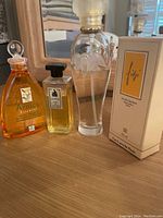 Photo of four perfumes on wooden surface including three used and one boxed item.