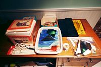 Table with Wen stained glass grinder machine in box, assorted stained glass pieces in tray and boxes, grinding tools and accessories, and plastic bags with stained glass shards.