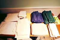 Full view of various folded tablecloths and napkins arranged by color and type on a wooden surface.