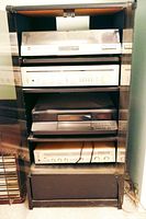 Audio equipment including Technics SL-33 turntable, two receivers/amplifiers, Sony CD player, all inside black cabinet with glass doors.