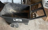 Photo showing black plastic yard cart wheel barrow with large wheels and ergonomic handle, used with dirt inside