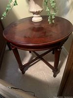 Photo of the top and part of the base of the oval end table showing the rich wood veneer finish and floral arrangement on top.