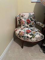 Front and side views of an antique 19th century wooden chair with curved legs and floral upholstery in multiple colors with a matching pillow on the seat.