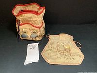 Front view of the square linen button bag showing needlepoint design of two children in blue with buttons and drawstring closure