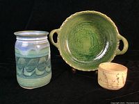 Overview photo of three pottery pieces: green glazed pie dish with handles, blue-green glazed vase, small signed bowl.