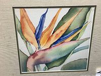 Close-up of watercolor painting showing Bird of Paradise flower detail and artist's signature.
