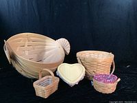 Front view of large snail-shaped basket next to heart-shaped box and smaller baskets