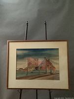 Framed watercolor artwork showing entire painting and frame on an easel.