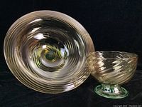 Both bowls visible from top angle showing swirl pattern and green bases on dark background.