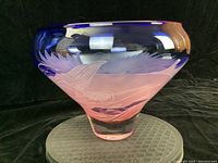 Front angle view of signed art glass bowl showing blue rim, pink base gradient, and etched feather-like designs.