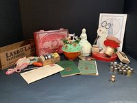 Full lot showing vintage sewing materials and accessories including thimbles, instruction manuals, scissors, spools, figurines, and decorative tins.