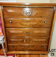 Front view of the wooden dresser showing five drawers with decorative carved panels and round knobs.