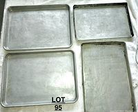 Four aluminum sheet pans arranged from largest to smallest with visible wear