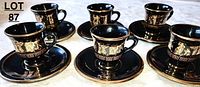 Photo showing 6 black espresso cups with matching saucers, all decorated with 24kt gold Greek-themed designs.