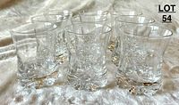 Nine small clear glass drinking glasses arranged together showing shape and design.