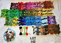 Large assortment of embroidery floss skeins in various colors arranged on a surface including greens, reds, pinks, yellows, blues, purples, browns.