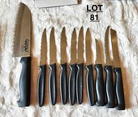 Full set of nine Ginsu knives laid out on a white towel, showing the large broad blade knife on the left and eight smaller knives to the right.