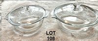 Top view showing two round glass baking dishes with lids and handles on side.