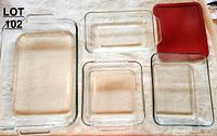 Top-down photo of five glass casserole dishes and one red lid showing all items in the set.