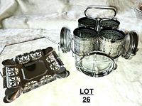 Four glasses with silver etched holders positioned in metal caddy, next to silver napkin holder with floral design