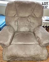 Front view of the brown recliner chair showing cushioned armrests and seat with tufted upholstery.