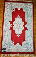 Top view of one decorative rug showing intricate floral pattern in red, beige, green, and pink tones with fringe on ends.
