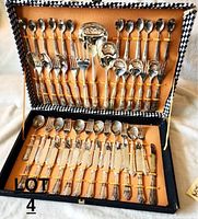 Full view of vintage cutlery set inside open box showing two layers of neatly arranged spoons, forks, knives, and serving utensils secured with orange bands.