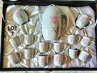 Top-down view of complete tea service set in original box, showing teapot, creamer, sugar bowl (without lid), and teacups arranged neatly on white satin lining.