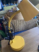 Yellow plug-in desk lamp with flexible neck and rectangular shade sitting on table.