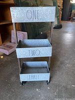 Full view of the 3 tier metal shelf bins with labels ONE, TWO, THREE and wheels