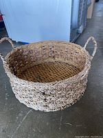 Wicker basket showing natural woven material with two handles, empty inside