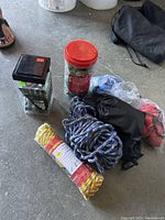 Photo of nine various ropes, bungee cords, and tie downs arranged on a concrete floor.