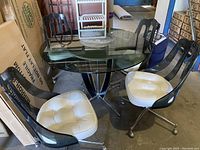 Full view of round smoked glass top table with four swivel chairs