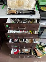 Opened black case containing carving set with brown handles including knife and fork, set inside a lined box.