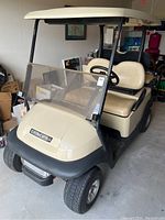 Front left side view of beige Custom Carts golf cart in garage