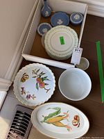 Box with six white Limoges plates with green trim, three blue Wedgwood jasperware dishes with white relief, and three Royal Worcester serving bowls featuring fruit decoration.