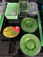 Overview of all items including green glass tea plates, clear and green butter dishes, ceramic cat spoon rest, and a rectangular dish