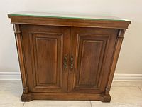 Front view of wooden hall table with paneled double doors and round column accents on sides.