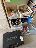 Overview photo showing stacked plastic bins with assorted wires, cables, fishing floaties, sandpaper, and black Durabuilt tool case on floor.