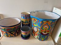 Wide view showing the four Mexican pottery items, two large planters, one small vase, and a tiny planter on a shelf.
