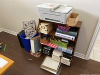 Office lot showing dark brown wooden bookshelf with various office supplies and items on shelves, including the HP printer on top.