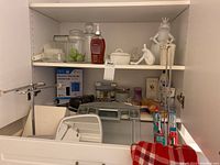 Lower shelf with digital blood pressure monitor, handheld mirror, weighing scales, toothbrushes, and towel holder