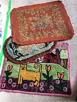 Photo showing three fabric pieces: floral upholstery fabric on top, and two colorful rug hooking patterns below with the cat and rabbit designs visible.